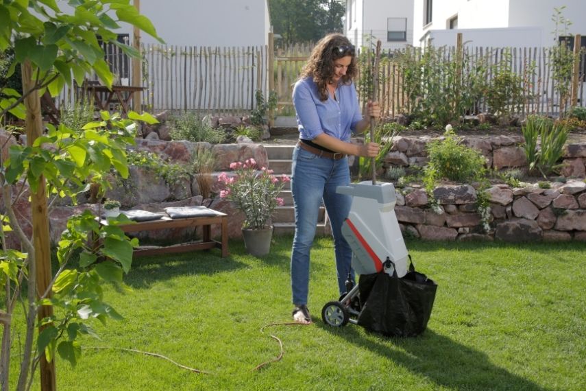 Eine Frau zerkleinert in einem Garten Schnittgut mit dem Elektro Messerhäcksler IMH 2500.