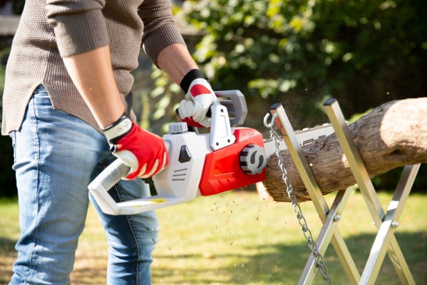 Eine Nahaufnahme zeigt, wie die Akku Kettensäge ICC 2/2035 bei der Arbeit an einem Holzbalken fest mit zwei Händen geführt wird.