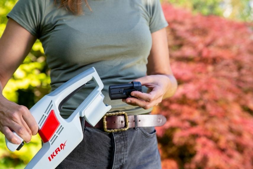 Frau setzt den 12 Volt Akku in die Akku Heckenschere IAHS 1240 ein.