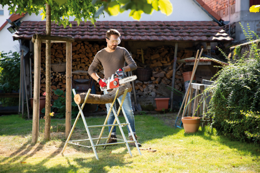 Mit der Akku Kettensäge ICC 2/2035 sägt ein Mann einen Baumstamm auf einem Metallbock.